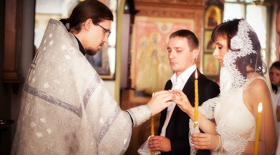Батюшка на обряде одевает кольца